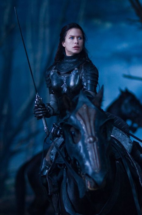 dark female warrior knight on black horse in black forest lit by ...